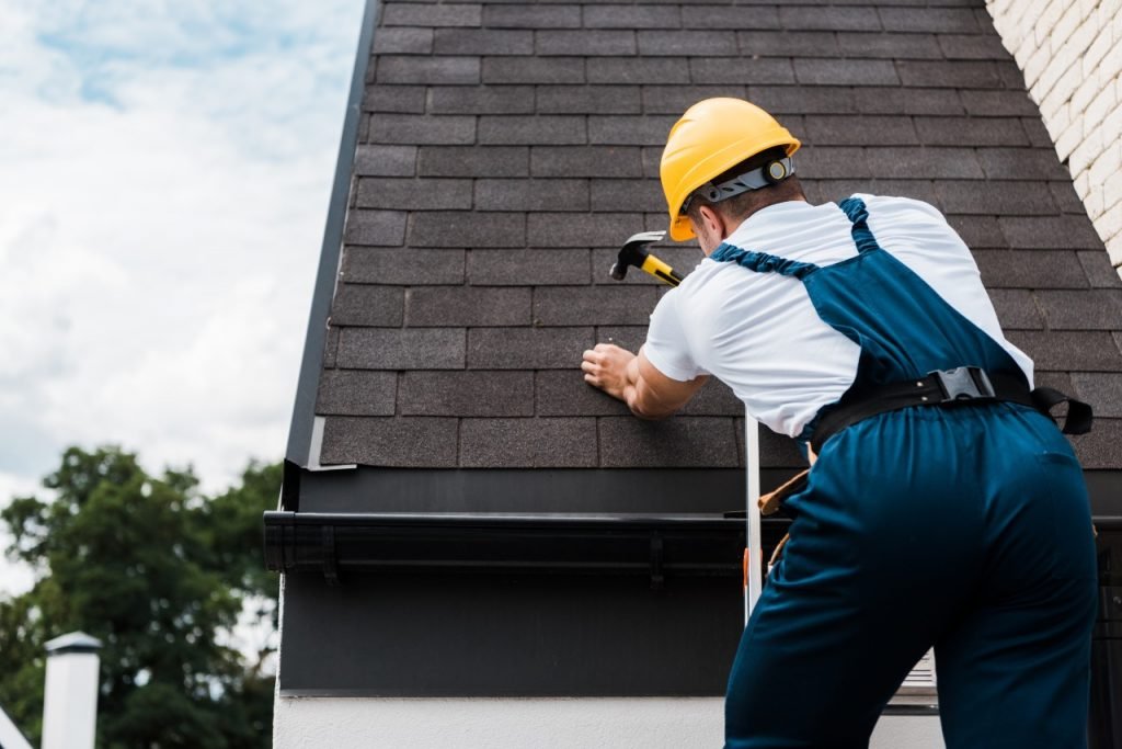 Roofer fixing a shingle roof